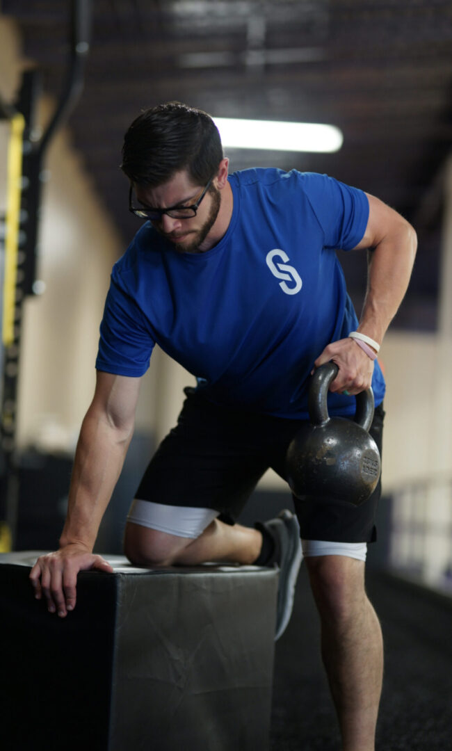 A man is holding a kettlebell in his hand.