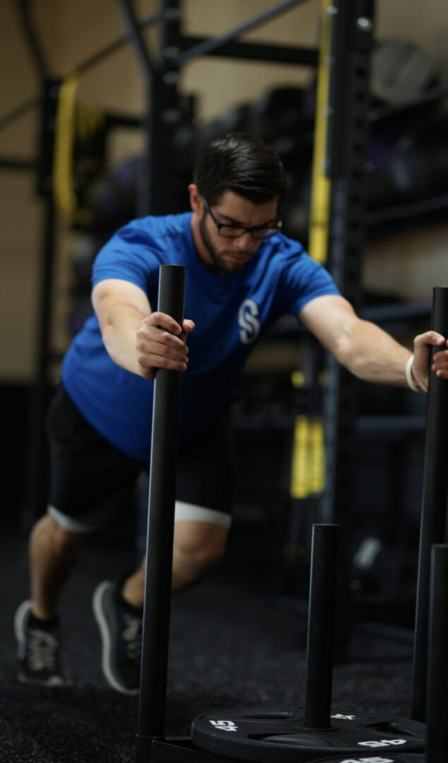 A man is pushing a sled in the gym.