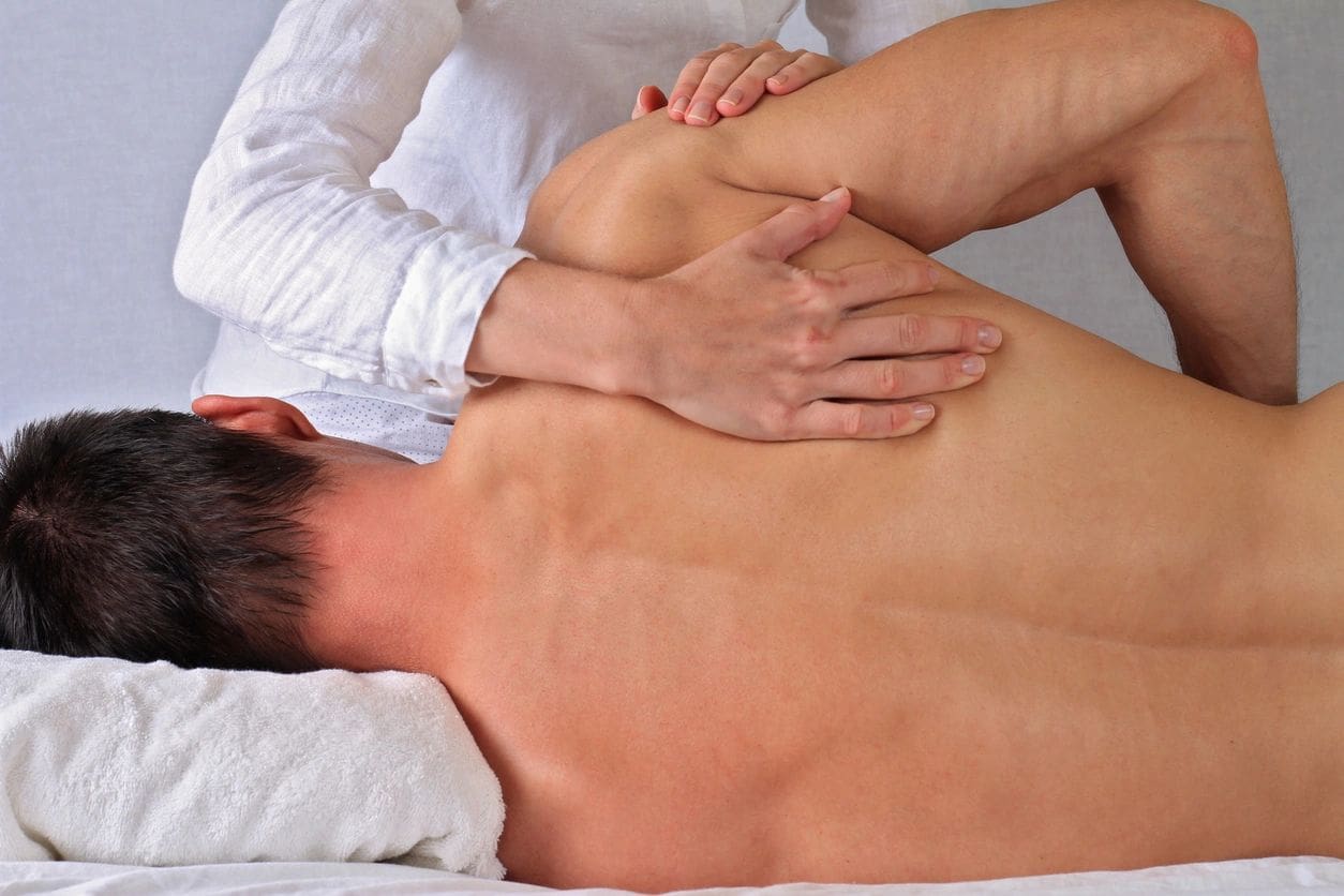 A man getting his back examined by an osteopath.